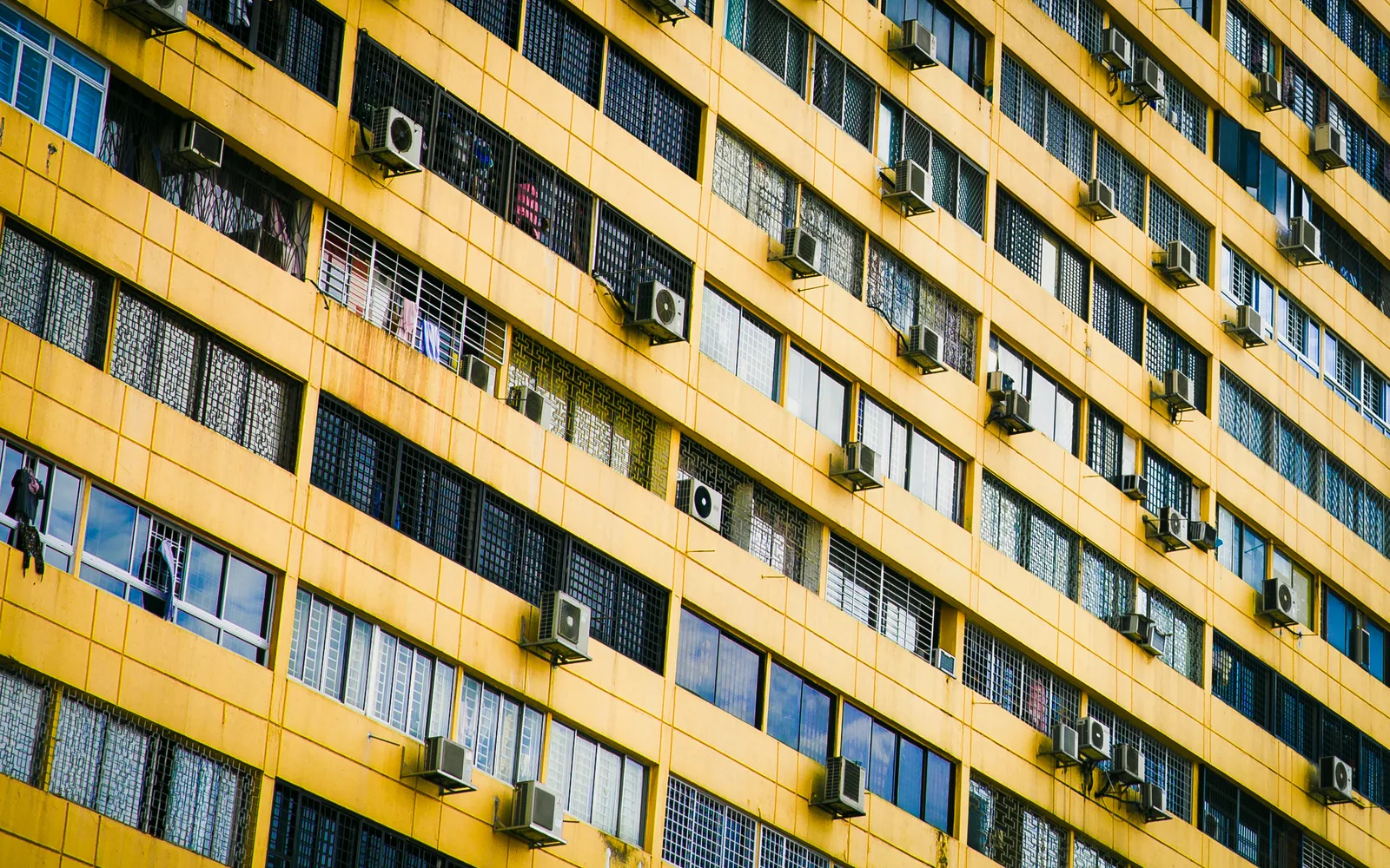 Bright yellow exterior wall of an apartment building with windows and architectural details
